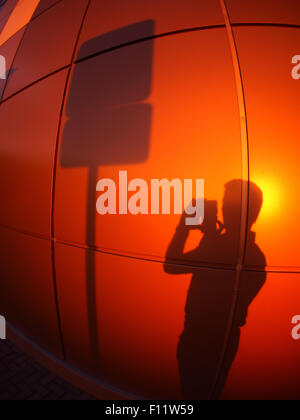 Die Silhouette eines Mannes an eine Wand rot-Orange, ein Schild am Abend bei Sonnenuntergang mit Weitwinkel fisheye-Objektiv fotografiert Stockfoto