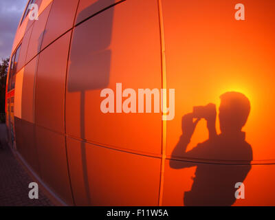 Die Silhouette eines Mannes an eine Wand rot-Orange, ein Schild am Abend bei Sonnenuntergang mit Weitwinkel fisheye-Objektiv fotografiert Stockfoto