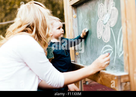 Schöne Mutter und Sohn auf Tafel mit Kreide zeichnen Stockfoto