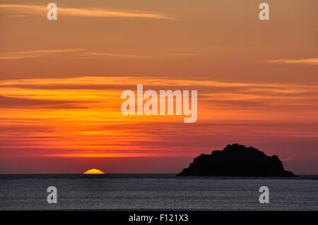 North Cornwall - untergehende Sonne Meer - Offshore-Insel in dunkle Silhouette - orange - rot-Gold Wolke gesprenkelt Himmel Stockfoto