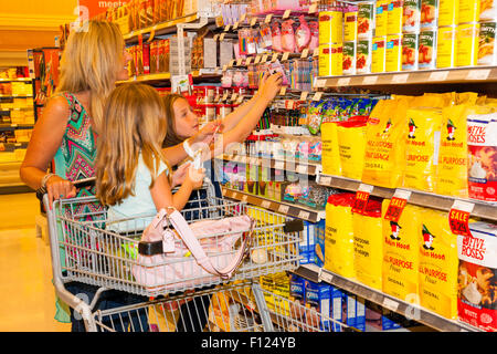 Mutter mit ihrem 2girls (Alter 6 und 9) sind in einem Supermarkt einkaufen und Produktetiketten für Ernährung Wert lesen lernen Stockfoto