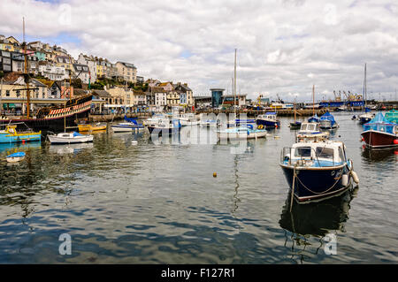 Pastell farbigen Häuser schmiegen sich über Geschäfte an der Promenade neben eine Vielzahl von Booten im malerischen Hafen von Brixham Stockfoto