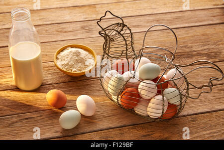 Eiern Mehl und Milch in einem Vintage Henne Form Korb auf Holz blau Ostern weiß und braun Stockfoto