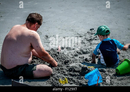 SPIELEN MATES, nimmt dieser Papa Timeout von seinem Urlaub etwas Erde bewegt sich mit seinem kleinen Jungen oder nur im Sand spielen zu tun. Stockfoto