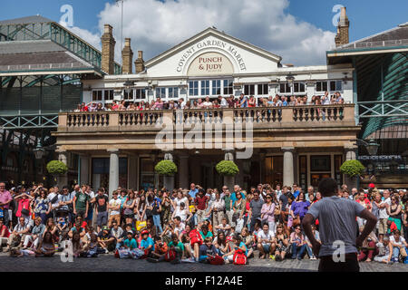Straßenkünstler unterhalten eine Menschenmenge an einem sonnigen Tag in Londons Covent Garden Piazza. Stockfoto