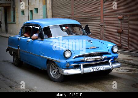 Blauer Oldtimer mit Passagiere fahren auf einer nassen Straße am Stadtrand von Havanna, Kuba Stockfoto