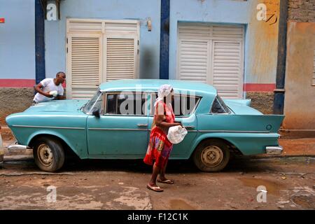 Blaues Vintage Auto geparkt auf dem Bürgersteig in einer Wohnstraße in Havanna, Kuba. Eine Dame ist Fuß durch und drückt ein Mann vorbei. Stockfoto