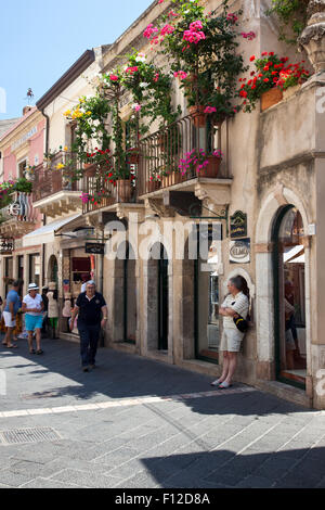 Hübsche Hauptstraße in der Altstadt von Taormina mit Balkonen voller Blumen, Sizilien, Italien Stockfoto