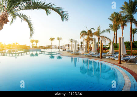 Swimming Pool und grossen grünen Palmen bei Sonnenaufgang Stockfoto