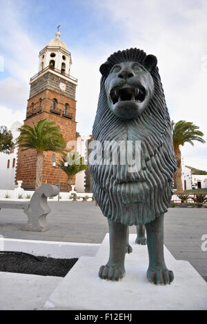 Löwenskulptur und Kirchturm der Kirche Nuestra Señora de Guadalupe an der Plaza de la Constitución (Teguise, Lanzarote, Kanarische Inseln, Spanien) Stockfoto