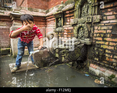 Kathmandu, Nepal. 1. August 2015. Ein kleiner Junge wäscht sein Gesicht mit Wasser aus einem öffentlichen Brunnen in einer Gemeinde in der Nähe von Durbar Square. Viele Häuser in der Gegend nicht Brauchwasser haben und Leute gehen noch zu Brunnen für ihr Wasser. Das Erdbeben im April 2015 beschädigt Infrastruktur, einschließlich der Wasser-System, in diesem Teil der Stadt. (Bild Kredit: Jack Kurtz/zReportage.com © über ZUMA Press) Stockfoto