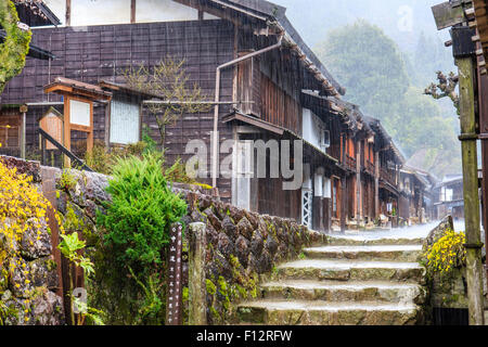 Tsumago, Japan. Terashita Straße auf dem alten Nakasendo Straße. Blick entlang der Edo Periode traditionelle 2-stöckiges Gebäude aus Holz in den strömenden Regen. Stockfoto