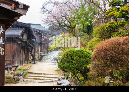 Tsumago, Japan. Terashita Straße auf dem alten Nakasendo Straße. Blick entlang der Edo Periode traditionelle 2-stöckiges Gebäude aus Holz in den strömenden Regen. Stockfoto