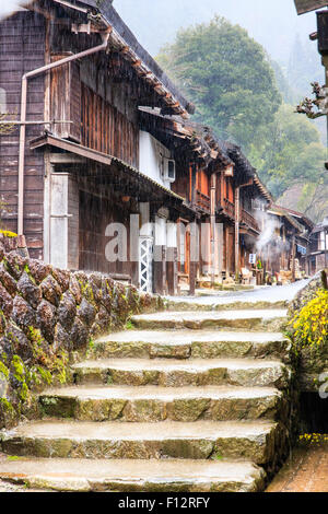 Tsumago, Japan. Terashita Straße auf dem alten Nakasendo Straße. Blick entlang der Edo Periode traditionelle 2-stöckiges Gebäude aus Holz in den strömenden Regen. Stockfoto