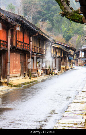 Tsumago, Japan. Terashita Straße auf dem alten Nakasendo Straße. Blick entlang der Edo Periode traditionelle 2-stöckiges Gebäude aus Holz in den strömenden Regen. Stockfoto