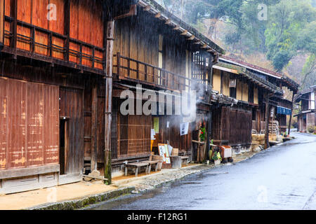 Tsumago, Japan. Terashita Straße auf dem alten Nakasendo Straße. Blick entlang der Edo Periode traditionelle 2-stöckiges Gebäude aus Holz in den strömenden Regen. Stockfoto