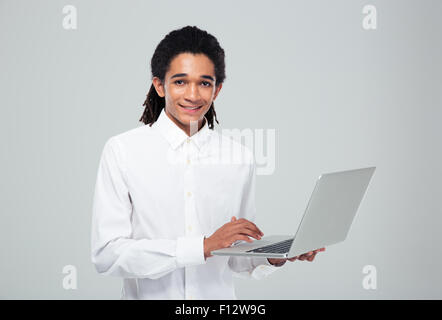 Porträt eines lächelnden Afro amerikanische Geschäftsmann mit Laptop und Blick in die Kamera über den grauen Hintergrund Stockfoto