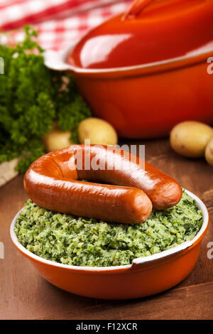 Ein rustikaler Tisch mit ein Gericht mit "trafen sich Boerenkool schlimmsten Fall" oder Grünkohl mit geräucherter Wurst, traditionelle niederländische Gerichte. Stockfoto