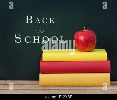 Roter Apfel auf den Bücherstapel. Tafel-Hintergrund mit Back to School-Text. Stockfoto