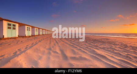 Eine Reihe von Strandhütten an einem Strand auf der Insel Texel in den Niederlanden. Am Sonnenuntergang fotografiert. Stockfoto