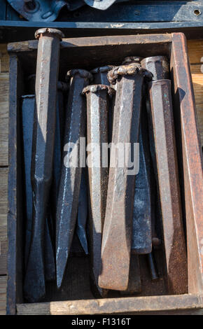 Eine Auswahl an alten kalten Meißel in einer Holzkiste auf einem Flohmarkt Stockfoto
