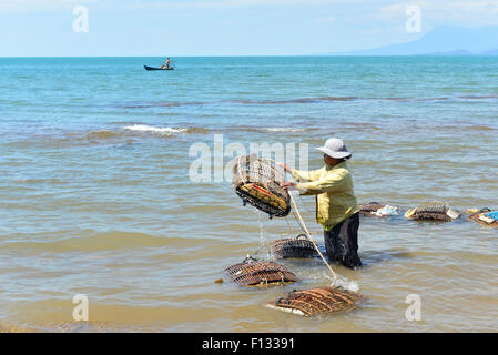 Frau Krabbenfalle ins Wasser zu werfen Stockfoto