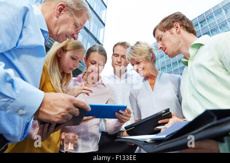 Geschäftsleute, die mit anderen Tablet-Computern in einer Besprechung Stockfoto