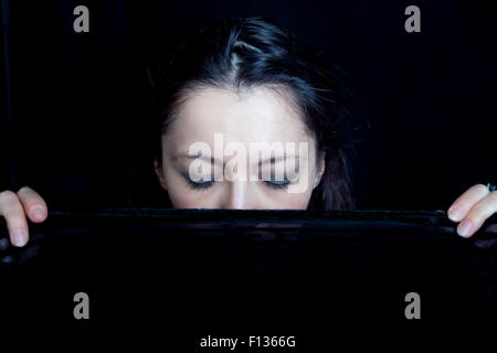 Frau mit ihren Augen geschlossen hält einen schwarzen Schleier vor ihrem Gesicht Stockfoto