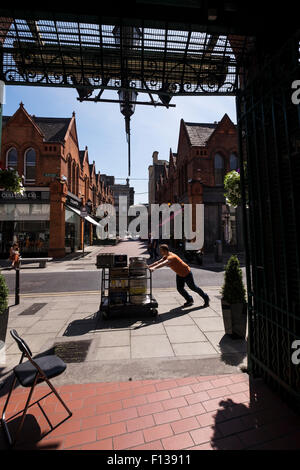 Lieferung Mann schieben Karren, beladen mit Bierfässern und Kisten von alkoholischen Getränken auf Drury Straße in Dublins Kreativquartier Stockfoto