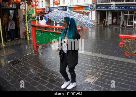 London, UK. Sonntag, 23. August 2015. Schwere Regen Sommerduschen im West End. Menschen mutig die Nässe, bewaffnet mit Sonnenschirme und wetterfeste Kleidung. Stockfoto