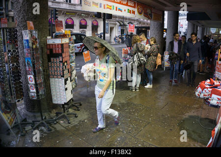 London, UK. Sonntag, 23. August 2015. Schwere Regen Sommerduschen im West End. Menschen mutig die Nässe, bewaffnet mit Sonnenschirme und wetterfeste Kleidung. Stockfoto