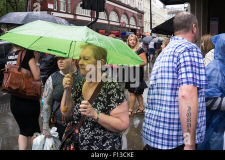 London, UK. Sonntag, 23. August 2015. Schwere Regen Sommerduschen im West End. Menschen mutig die Nässe, bewaffnet mit Sonnenschirme und wetterfeste Kleidung. Stockfoto