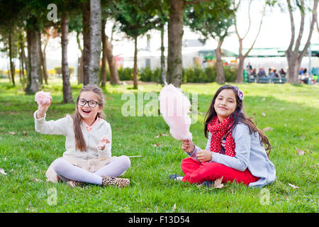 Zwei Mädchen sitzen im Park essen Zuckerwatte Stockfoto