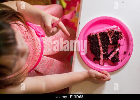 Blick von oben auf das Mädchen, das an einem Tisch sitzt und ein Stück Chocolatecake isst Stockfoto