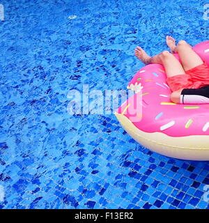 Entspannen Sie sich auf aufblasbaren Donut in einem Schwimmbad reifer Mann Stockfoto