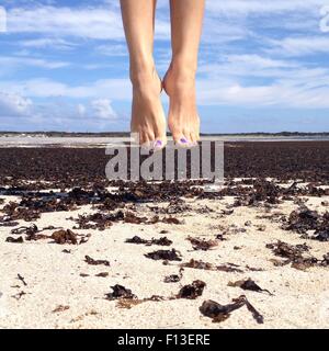 Frau springt am Strand in die Luft Stockfoto