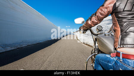 Biker Girl reitet auf eine Bergstraße mit hohen Schneewand in Norwegen. First-Person-Ansicht. Stockfoto