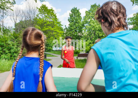 Vier Teenager Freunde spielen Pingpong außerhalb Stockfoto