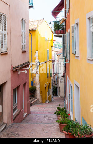 VILLEFRANCHE-SUR-MER, Frankreich-4. Oktober 2014: Schmale Straße mit leuchtend bunten Gebäuden führt zu Mittelmeer in medie Stockfoto