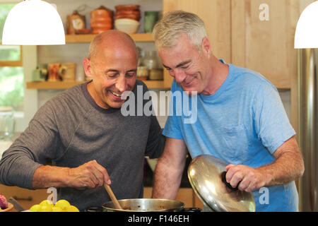 Senior Homosexuell männlichen Partner, lächelnd und liebevoll, im Urlaub und zusammen kochen in ihrer Küche Stockfoto
