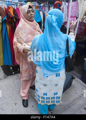 Frauen in Bangladesch sprechen, da sie für Kleidung bei Street Shop fair in "Little Bangladesch" in Brooklyn, New York. Stockfoto