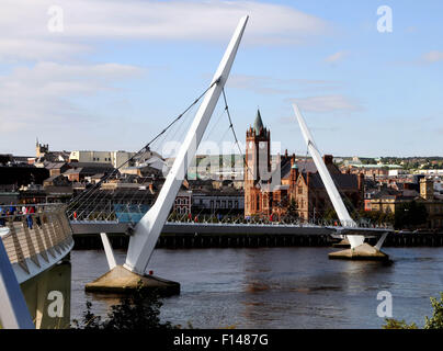 Irland-LONDONDERRY der spektakulären Friedensbrücke über den Fluss Foyle mit der Gilden-Halle im Hintergrund. Stockfoto