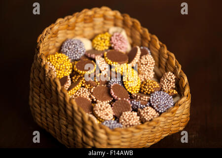 Bunte Schoko Dragees im Korb auf einem hölzernen Hintergrund platziert Stockfoto