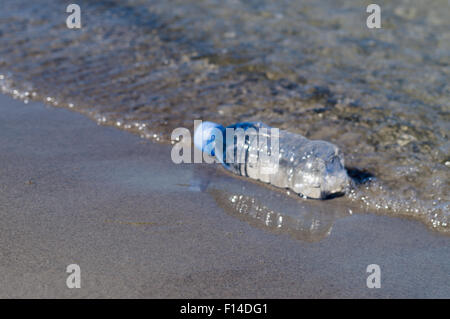 Verschwommene Flasche frisches Wasser am Ufer des Meeres, Trinkwasser-Konzept Stockfoto