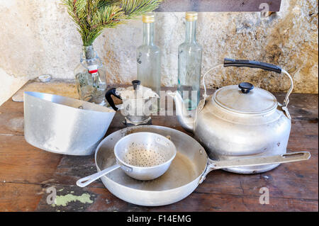 Alte Küchengeräte aus Aluminium. Von alten Holzbalken, Sieb, Pfannen, Wasserkocher hängen: Pfannen, Sieb, Wasserkocher, Kaffeemaschine und Dre Stockfoto