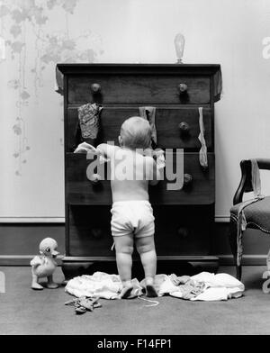 1940ER JAHREN KLEINKIND BABY ZIEHEN KLEIDER AUS BÜRO SCHUBLADEN EIN CHAOS Stockfoto