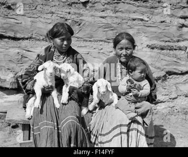 1930ER JAHREN ZWEI INDIANISCHE NAVAJO FRAUEN HALTEN BABY UND 3 KLEINE LÄMMER Stockfoto