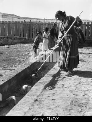 1930ER JAHREN INDIANISCHE FRAUEN KINDER FÜHRENDEN SCHAFE DURCH SCHAFE TAUCHEN IN TUBA CITY IN ARIZONA-NAVAJO-INDIANER-RESERVAT Stockfoto