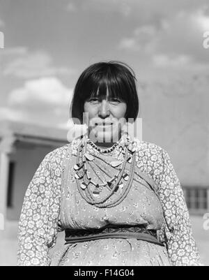 1930ER JAHRE PORTRAIT INDIANISCHE FRAU, DIE AN KAMERA TRAGEN TYPISCHE TRACHTEN UND SCHMUCK SAN ILDEFONSO PUEBLO NEW MEXICO Stockfoto