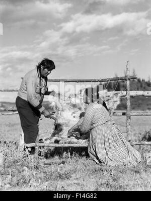 1920ER JAHREN INDIANISCHE PAAR MANN FRAU BEHANDLUNG VON TIERHAUT HAUT STONEY SIOUX ALBERTA KANADA Stockfoto